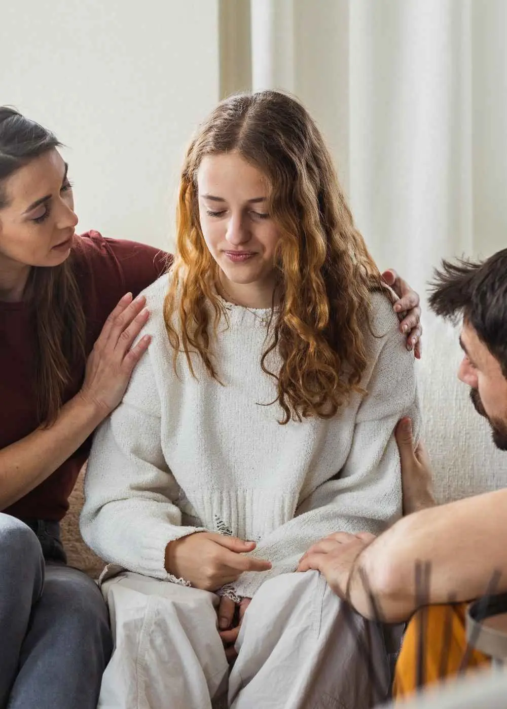 Young woman receiving emotional support from two people during therapy session