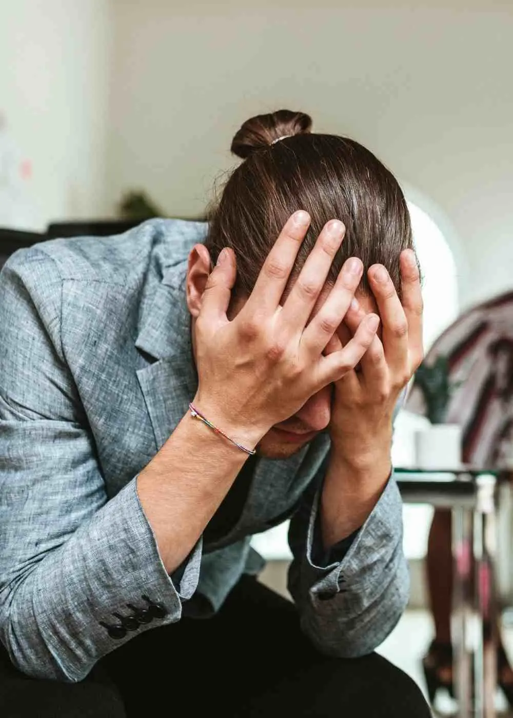 Man sitting with hands on head showing signs of severe anxiety and emotional stress