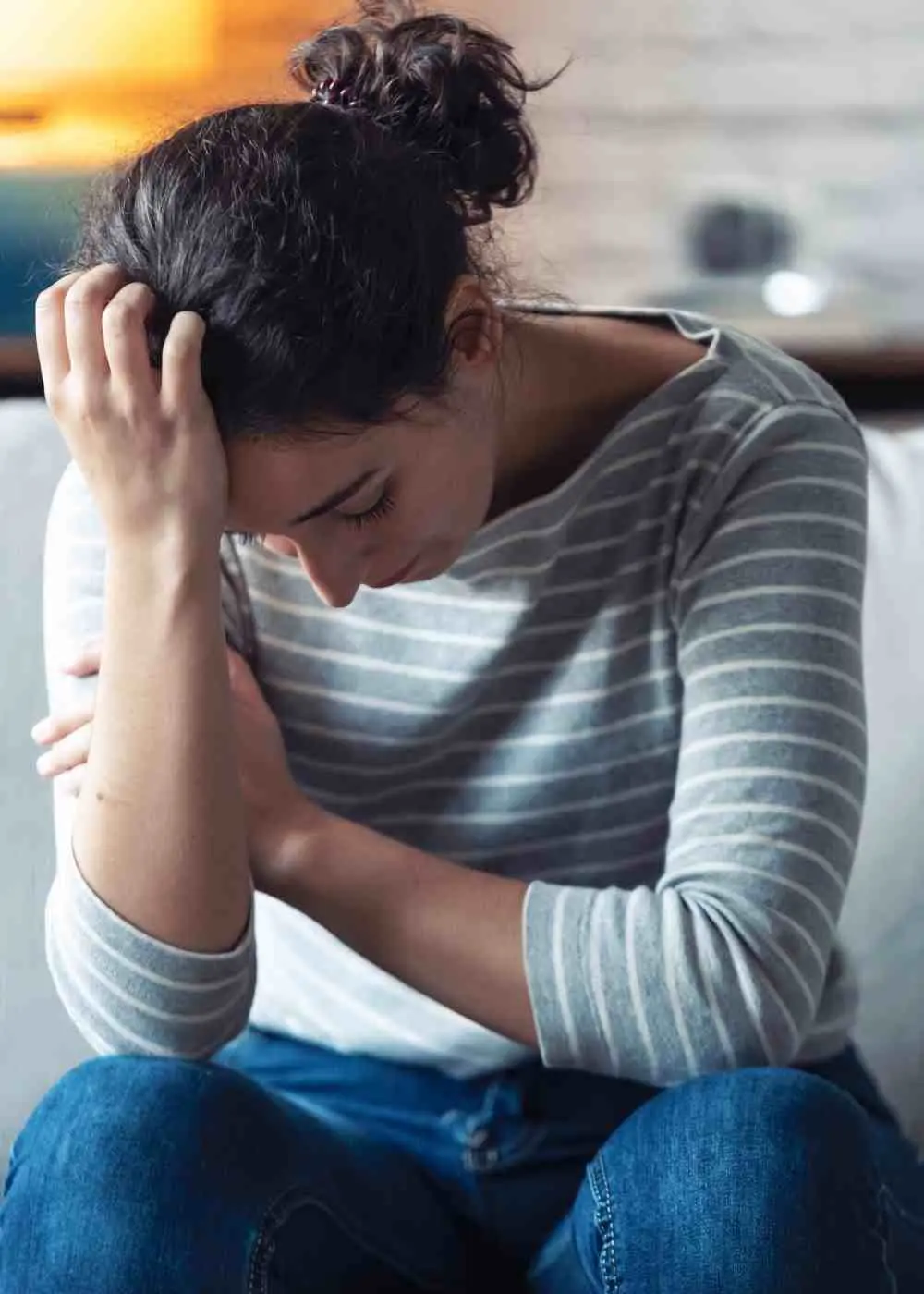 Woman sitting on couch holding head showing fatigue and high-functioning depression symptoms
